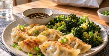 An inviting dinner plate of cooked vegetable dumplings with bright broccoli, scallions and a small dipping sauce, a closed plain unbranded frozen-food bag far in the background